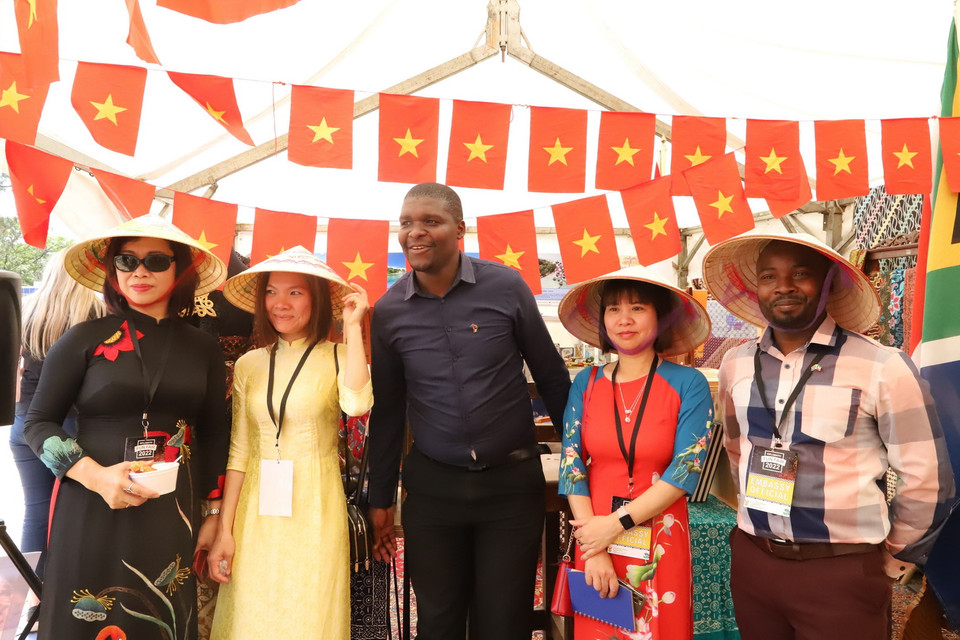 Du khách thích thú việc đội thử chiếc nón lá Việt Nam khi đến thăm quầy giới thiệu. (Ảnh: Hồng Minh/TTXVN)