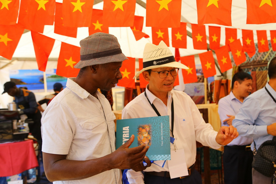 Đại sứ Việt Nam tại Nam Phi Hoàng Văn Lợi (phải) giới thiệu với bạn bè quốc tế về văn hóa và ẩm thực Việt Nam tại Hội chợ Ngoại giao Nam Phi 2022. (Ảnh: Hồng Minh/TTXVN)