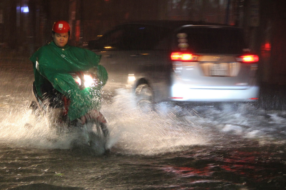 Các phương tiện lưu thông trên đường ngập nước. (Ảnh: Xuân Dự/TTXVN)