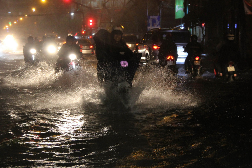 Các phương tiện lưu thông trên đường ngập nước. (Ảnh: Xuân Dự/TTXVN)