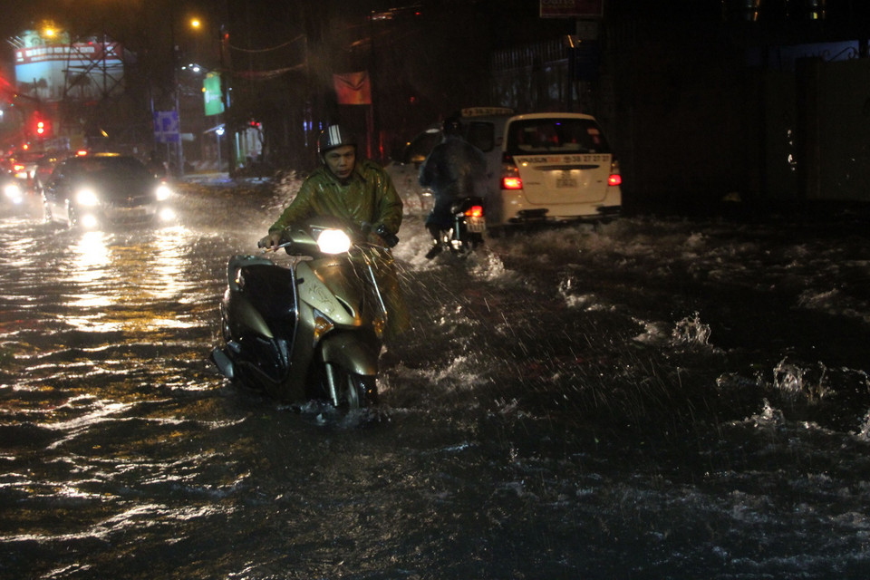 Nước ngập sâu khiến nhiều xe bị chết máy phải dắt bộ. (Ảnh: Xuân Dự/TTXVN)