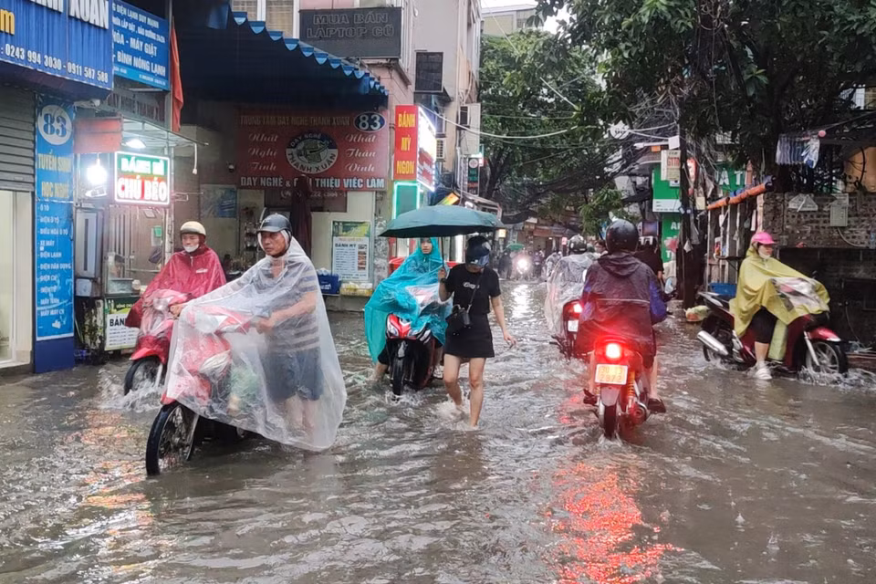 Nhiều người dân gặp tình trạng xe chết máy, phải xuống dắt bộ qua khu vực nước ngập. (Ảnh: Hoài Nam/Vietnam+)