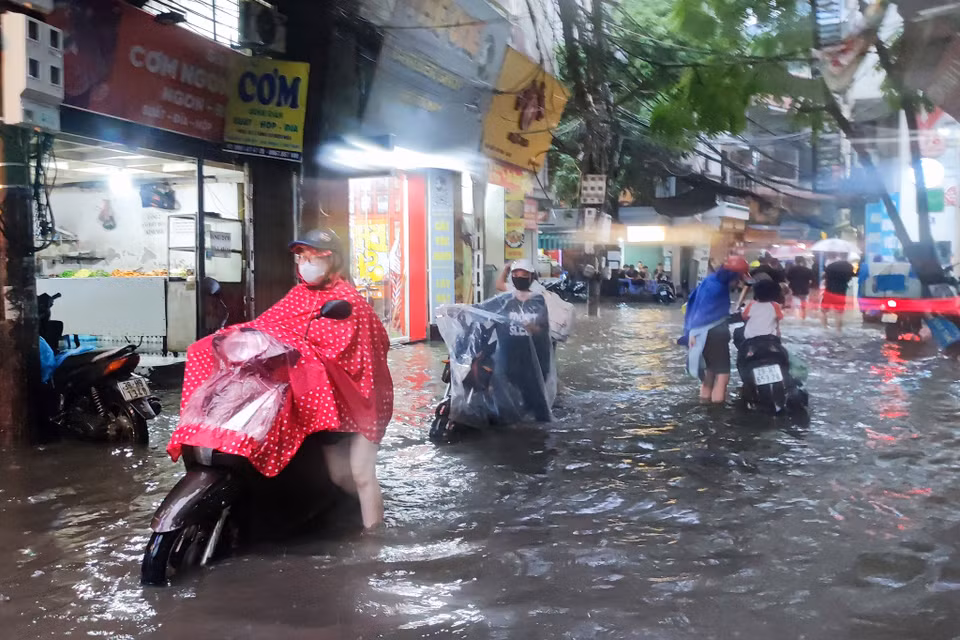 Người dân Thủ đô dắt xe qua khu vực nước ngập sâu. (Ảnh: Hoài Nam/Vietnam+)