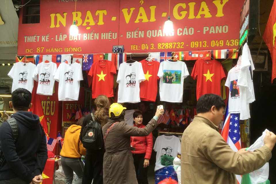 Du khách chọn mua áo có in hình Tổng thống Mỹ Donald Trump và Chủ tịch Triều Tiên Kim Jong-un tại một cửa hàng trên phố Hàng Bông. (Ảnh: Quang Hải/TTXVN)