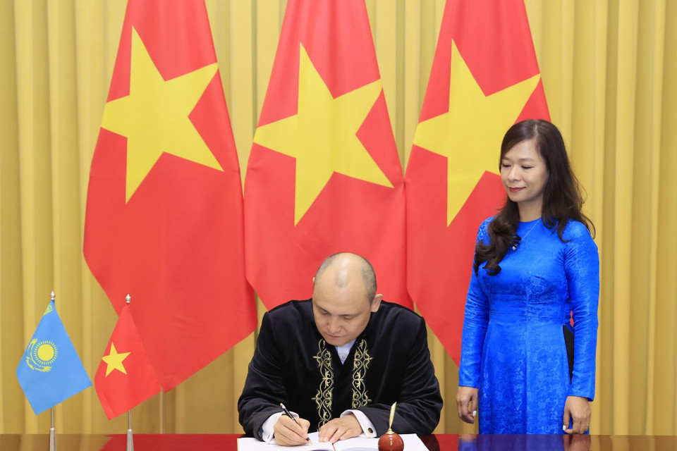 Đại sứ Kazakhstan Kanat Tumysh viết lưu bút. (Ảnh: Thống Nhất/TTXVN)