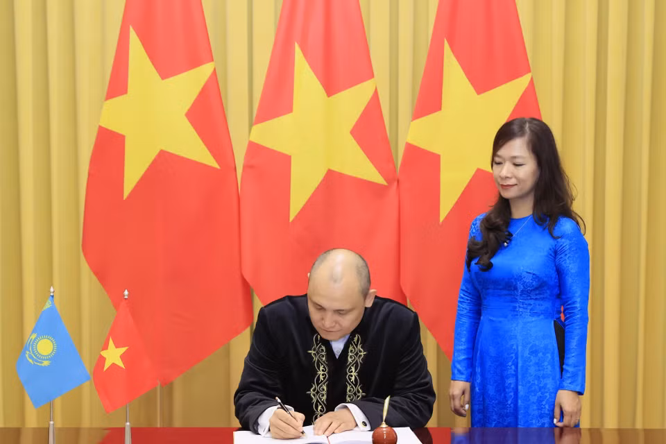 Đại sứ Kazakhstan Kanat Tumysh viết lưu bút. (Ảnh: Thống Nhất/TTXVN)