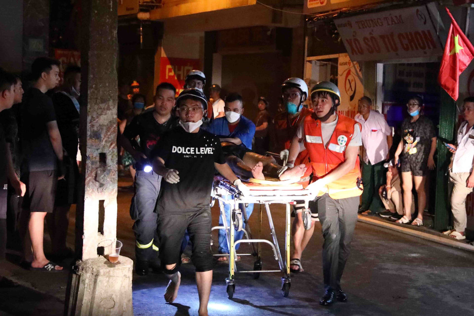 Lực lượng chức năng đưa các nạn nhân ra bên ngoài. (Ảnh: Phạm Kiên/TTXVN)