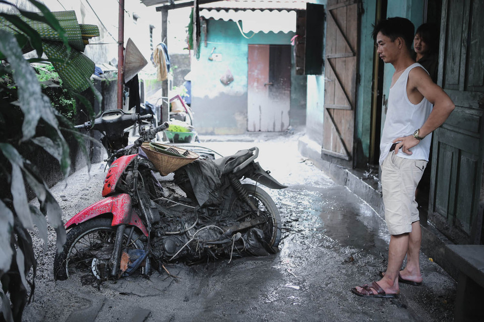 Người dân đau lòng nhìn 2 chiếc xe máy vừa được lôi lên từ đống bùn đã bị hư hại hoàn toàn. (Ảnh: Minh Sơn/Vietnam+)