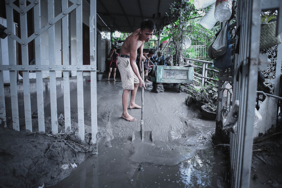 Mọi người dân trong các khu bị ngập hỗ trợ nhau dọn bùn đất. (Ảnh: Minh Sơn/Vietnam+)