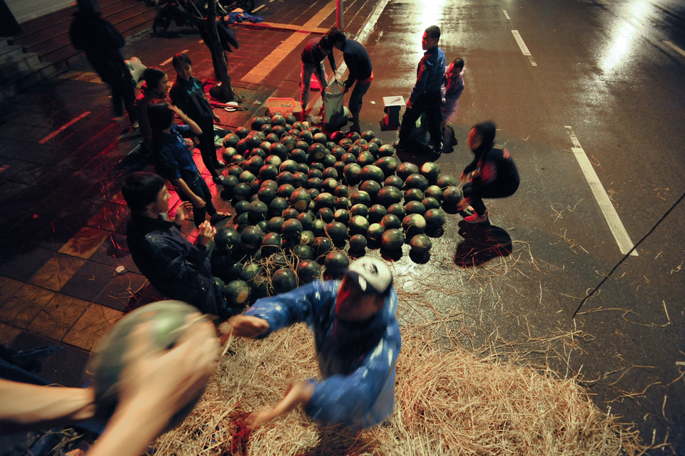 Sau khi chuyển dưa hấu từ xe tải lớn xuống, từng quả dưa hấu sẽ được cân và chuyển qua xe tải nhỏ chở đến các điểm bán trong Hà Nội. (Ảnh: PV/Vietnam+)