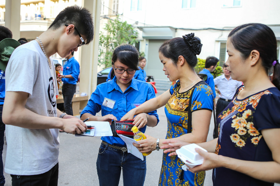 Một số phụ huynh thắc mắc với tình nguyện viên khi không được mang vỏ máy tính hay chai nước vào phòng thi. (Ảnh: Minh Sơn/Vietnam+)