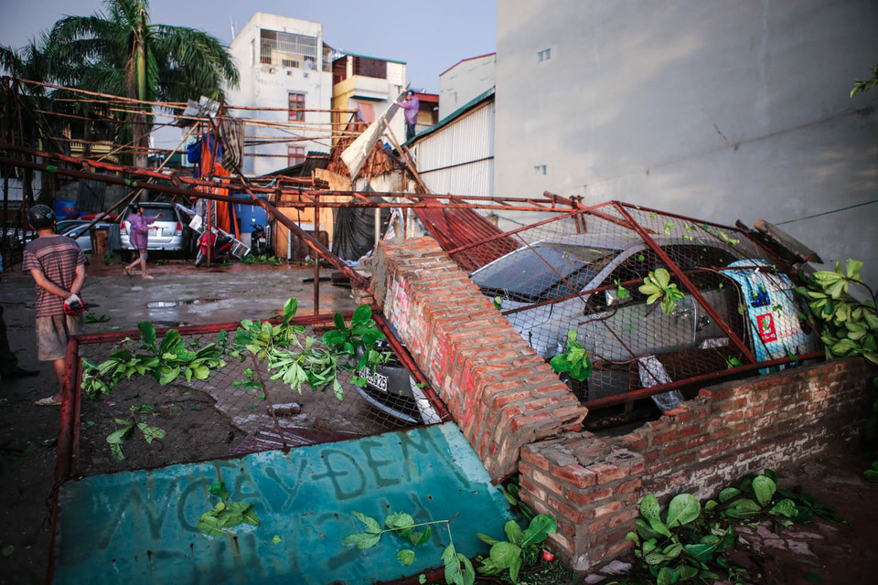 Trận dông lốc cực mạnh đã khiến cho hàng loạt cây cối bị đổ, thậm chí kéo đổ cả một bức tường rào lên xe ô tô, may mắn người chủ xe đã thoát ra kịp thời. (Ảnh: Minh Sơn/Vietnam+)