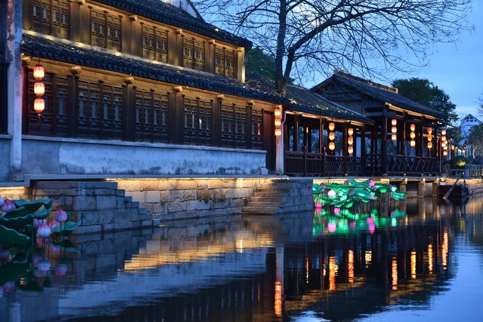 Ngay lối vào, khi màn đêm buông xuống, một góc cổ trấn hiện lên với những mái nhà cổ lung linh trong ánh đèn bên hồ. (Ảnh: Tiến Trung-Thành Dương/Vietnam+)