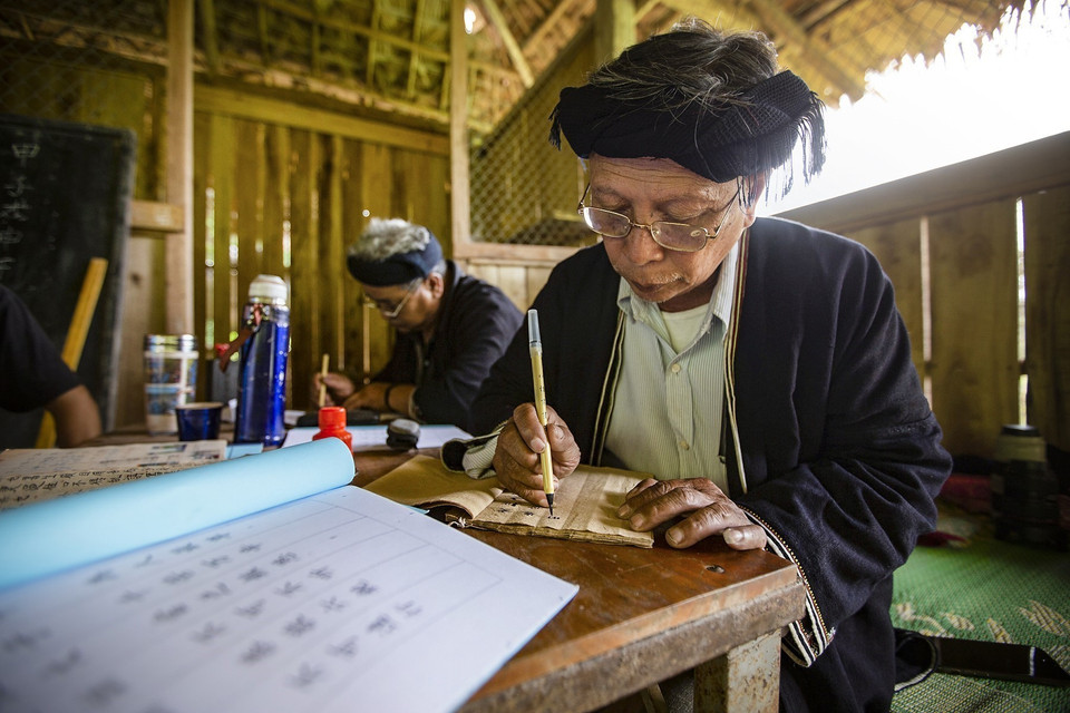 Những khi rảnh rỗi, ông Lý Văn Hềnh miệt mài viết và biên soạn những bộ chữ viết của dân tộc Dao Tiền để truyền dạy cho con cháu và các học viên. (Ảnh: Trọng Đạt/TTXVN)