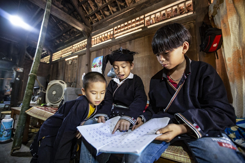 Ba người cháu được ông Lý Văn Hềnh truyền dạy chữ Dao mỗi ngày tại nhà. (Ảnh: Trọng Đạt/TTXVN)