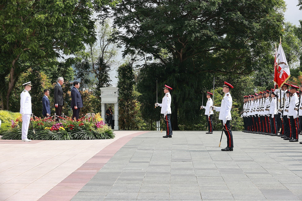 Thủ tướng Phạm Minh Chính và Thủ tướng Singapore Lý Hiển Long nghe quân nhạc cử Quốc thiều hai nước. (Ảnh: Dương Giang/TTXVN)