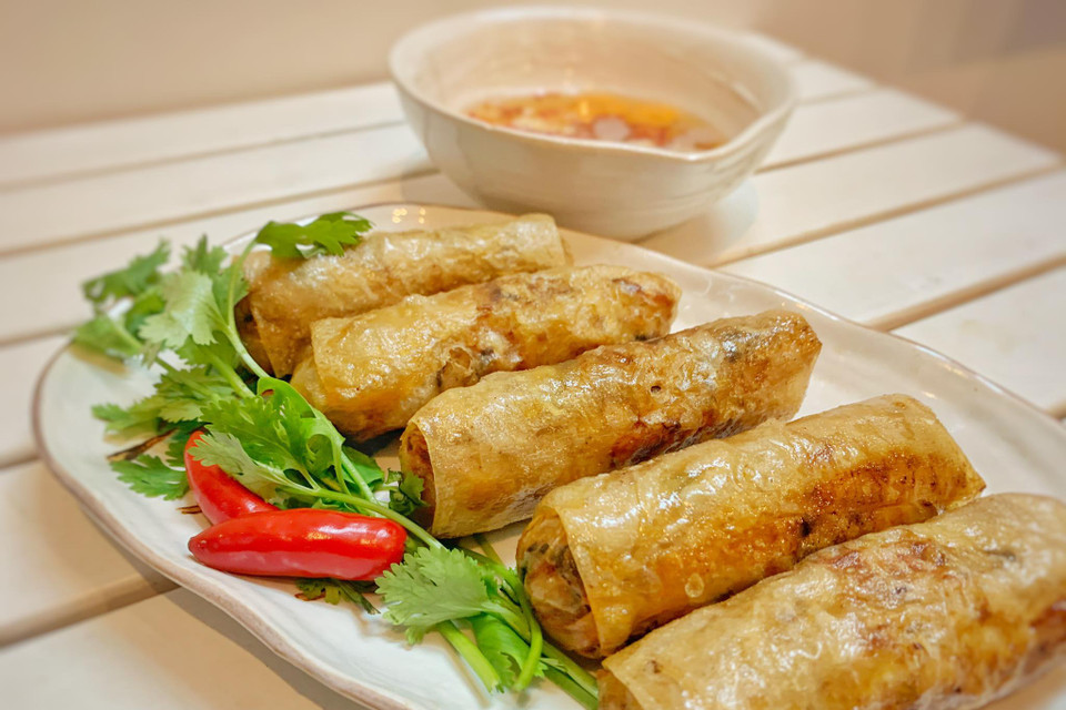 Cho ra đĩa và thưởng thức cùng rau sống, nước mắm ngon, ăn kèm bún hoặc cơm. Cách pha nước chấm nem: pha đúng tỉ lệ 1:1:1:5 theo thành phần nước mắm, giấm, đường, nước lọc, rồi cho tỏi, ớt băm vào bát nước chấm, khuấy đều. (Ảnh: Mai Mai/Vietnam+)