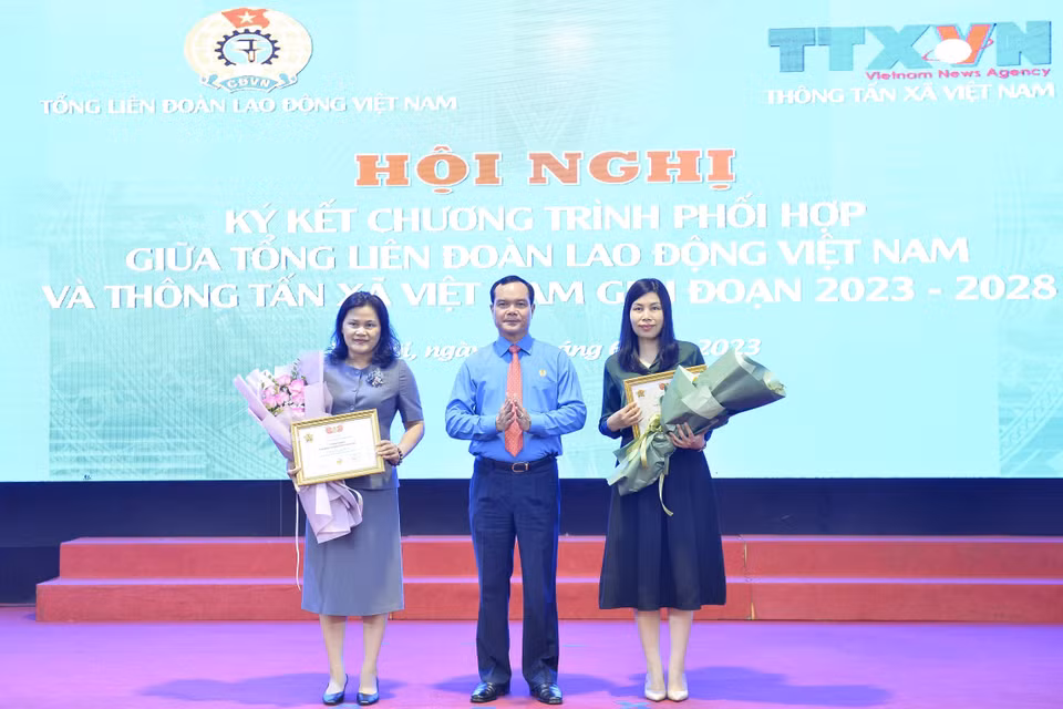 Chủ tịch Tổng Liên đoàn Lao động Việt Nam Nguyễn Đình Khang trao tặng Kỷ niệm chương "Vì sự nghiệp xây dựng tổ chức Công đoàn" cho 2 cán bộ của Thông tấn xã Việt Nam. (Ảnh: Minh Đức/TTXVN) 