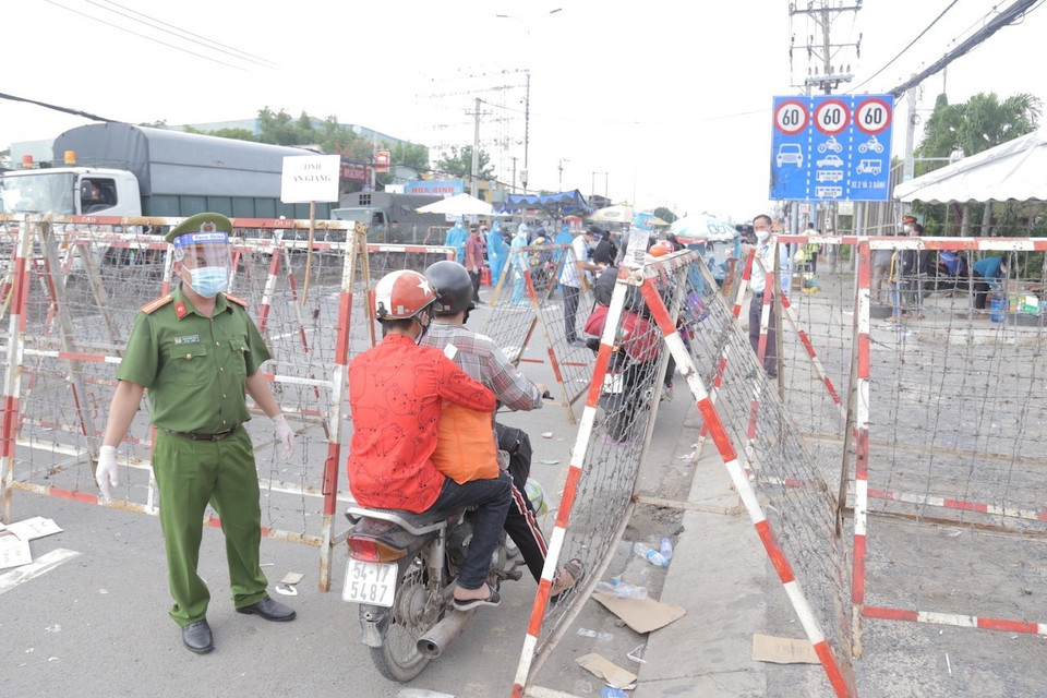Lực lượng công an phân luồng, đảm bảo an ninh trật tự tại khu vực người dân tập trung trên Quốc lộ 1, đoạn qua Thị trấn Tân Túc, huyện Bình Chánh, Thành phố Hồ Chí Minh. (Ảnh: TTXVN phát)