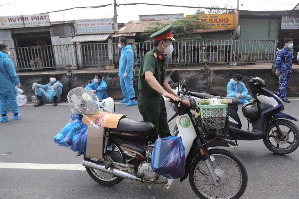 Lực lượng kiểm soát quân sự vận chuyển xe máy cho người dân lên xe ôtô chở về quê. (Ảnh: TTXVN phát)
