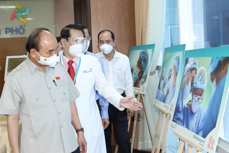 Chủ tịch nước Nguyễn Xuân Phúc xem một số hình ảnh về Dấu ấn song sinh 2000 được trưng bày tại bệnh viện. (Ảnh: Thống Nhất/TTXVN)