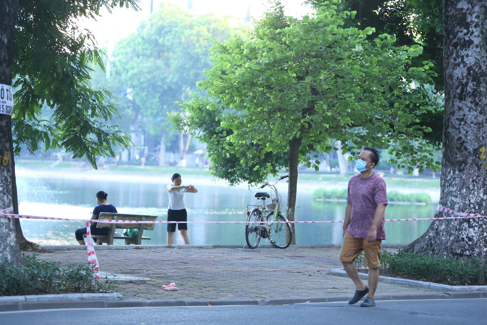 Nhiều người dân vẫn tập thể dục tại khu vực hồ Thiền Quang dù đã được lực lượng chức năng căng dây, cắm biển cấm (ảnh chụp lúc 5h50 ngày 13/7). (Ảnh: Hoàng Hiếu/TTXVN)