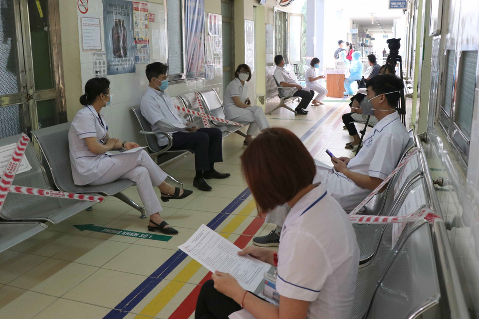 Sau quá trình khám, sàng lọc người chờ tiêm vaccine phòng COVID-19 được bố trí đảm bảo giãn cách ngoài hành lang. (Ảnh: Xuân Tiến/TTXVN)