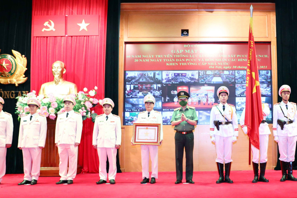 Thừa ủy quyền của Chủ tịch nước, Đại tướng Tô Lâm, Ủy viên Bộ Chính trị, Bộ trưởng Bộ Công an gắn Huân chương Quân công hạng Nhì lên cờ truyền thống của Cục cảnh sát Phòng cháy chữa cháy và cứu nạn cứu hộ. (Ảnh: Phạm Kiên/TTXVN)