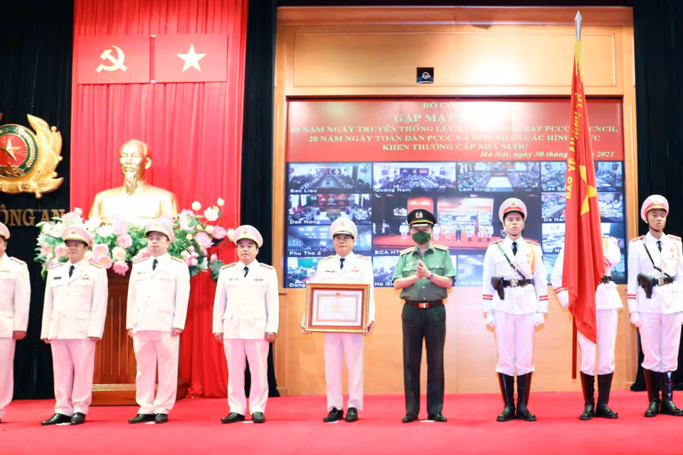 Thừa ủy quyền của Chủ tịch nước, Đại tướng Tô Lâm, Ủy viên Bộ Chính trị, Bộ trưởng Bộ Công an gắn Huân chương Quân công hạng Nhì lên cờ truyền thống của Cục cảnh sát Phòng cháy chữa cháy và cứu nạn cứu hộ. (Ảnh: Phạm Kiên/TTXVN)