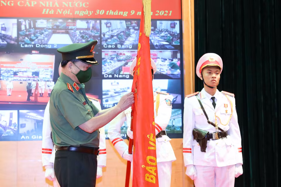 Đại tướng Tô Lâm, Ủy viên Bộ Chính trị, Bộ trưởng Bộ Công an thừa ủy quyền của Chủ tịch nước gắn Huân chương Quân công hạng Nhì lên cờ truyền thống của Cục cảnh sát Phòng cháy chữa cháy và cứu nạn cứu hộ. (Ảnh: Phạm Kiên/TTXVN)