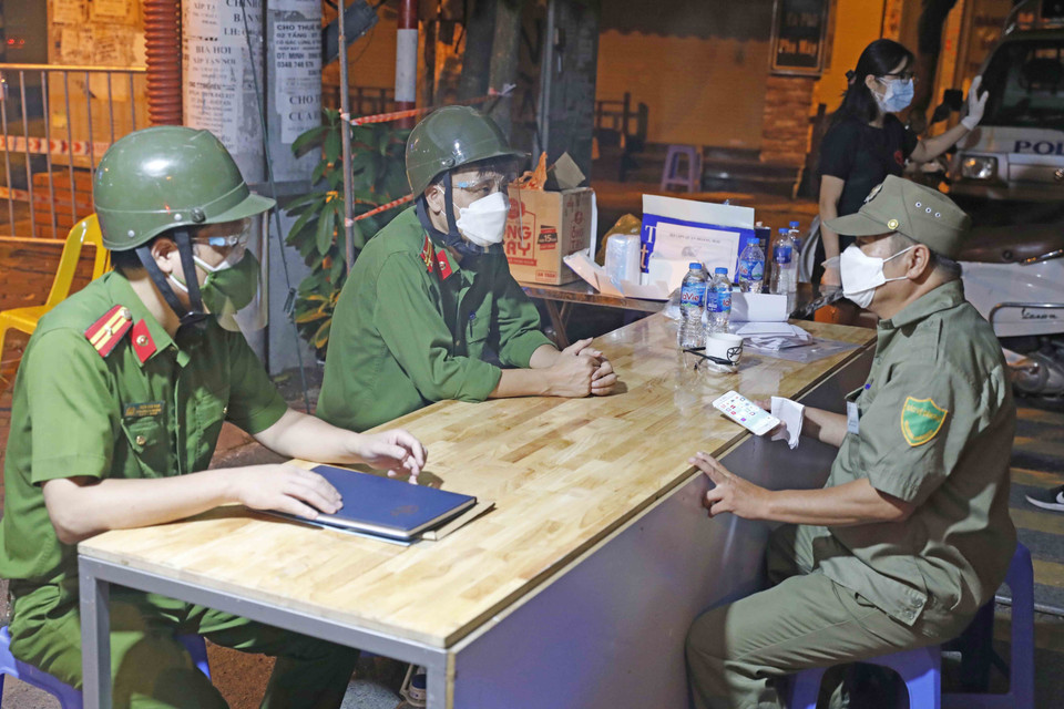 Bàn giao ca trực tại chốt cách ly ở ngõ 24, phố Kim Đồng, phường Giáp Bát, quận Hoàng Mai. (Ảnh: Trần Việt/TTXVN)