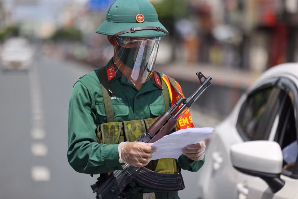 Lực lượng quân sự chịu trách nhiệm phối hợp, hỗ trợ công an ra hiệu lệnh điều người, phương tiện đang di chuyển trên đường; kiểm tra thông tin người đi đường. (Ảnh: Ngô Trần Hải An/Vietnam+)