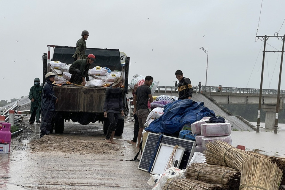 Lực lượng chức năng hỗ trợ di dời tài sản của người dân vùng lũ đến nơi an toàn. (Ảnh: Quang Thái/TTXVN)