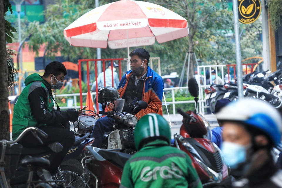Một lái xe công nghệ không đeo khẩu trang đúng quy cách trong lúc chờ giao nhận hàng. (Ảnh: Tuấn Anh/TTXVN)