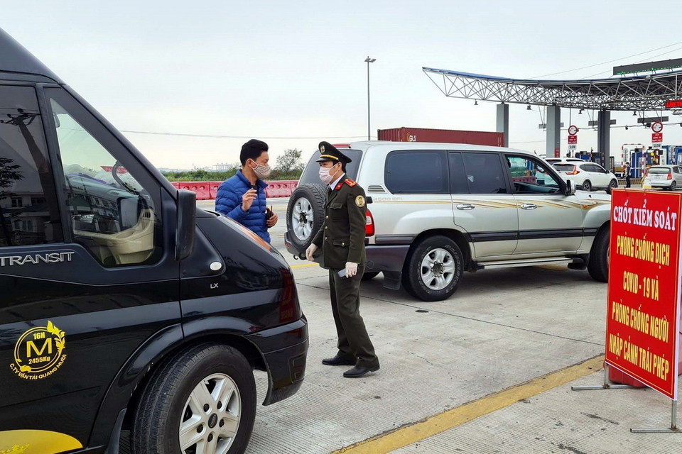 Lực lượng chức năng làm nhiệm vụ hướng dẫn, phân luồng giao thông, khai báo y tế tại chốt trạm cầu Bạch Đằng, thị xã Quảng Yên. (Ảnh: TTXVN)