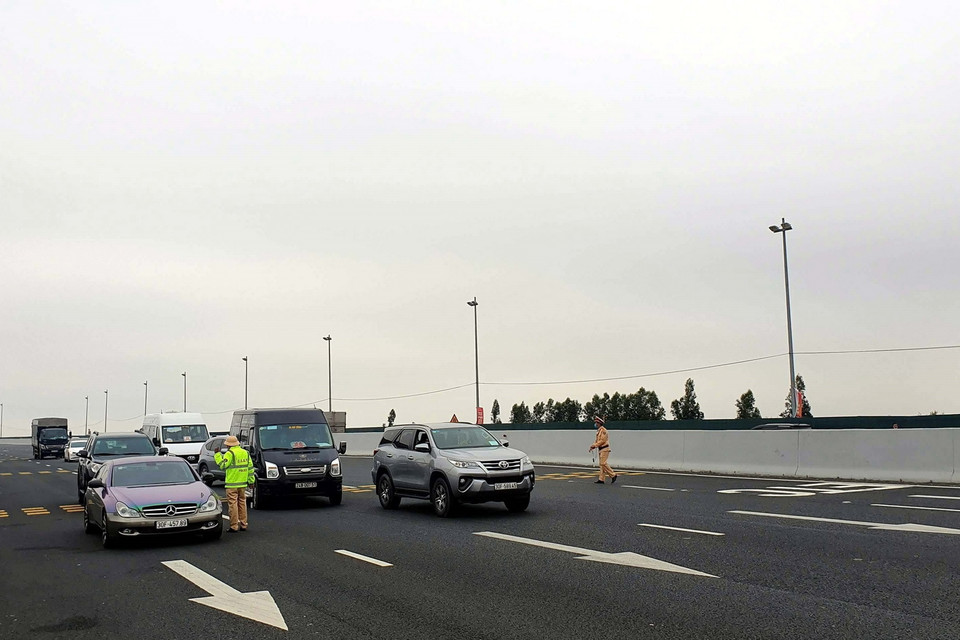  Lực lượng chức năng làm nhiệm vụ hướng dẫn, phân luồng giao thông, khai báo y tế tại chốt trạm cầu Bạch Đằng, thị xã Quảng Yên. (Ảnh: TTXVN)