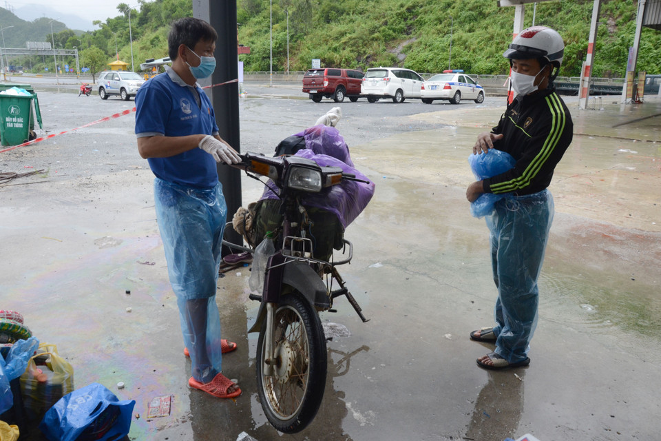Anh Phan Thanh Tin, đại diện Nhóm thiện nguyện Bánh mì 0 đồng Đà Nẵng (bên trái) kiểm tra xe anh Nguyễn Quang Bình (bên phải) và cho biết sẽ tặng một chiếc xe máy mới. (Ảnh: Quốc Dũng/TTXVN)