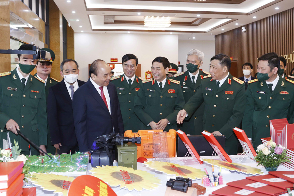 Hình ảnh Chủ tịch nước Nguyễn Xuân Phúc và các đại biểu tham quan gian trưng bày các ấn phẩm của Học viện Quốc phòng. (Ảnh: Thống Nhất/TTXVN)