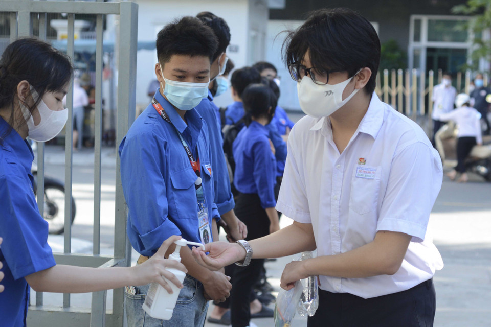 Học sinh được đo thân nhiệt, rửa tay bằng nước sát khuẩn trước khi vào phòng thi. (Ảnh: Văn Dũng/TTXVN)