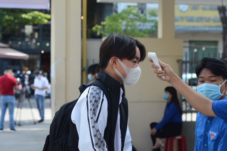 Học sinh được đo thân nhiệt, rửa tay bằng nước sát khuẩn trước khi vào phòng thi. (Ảnh: Văn Dũng/TTXVN)