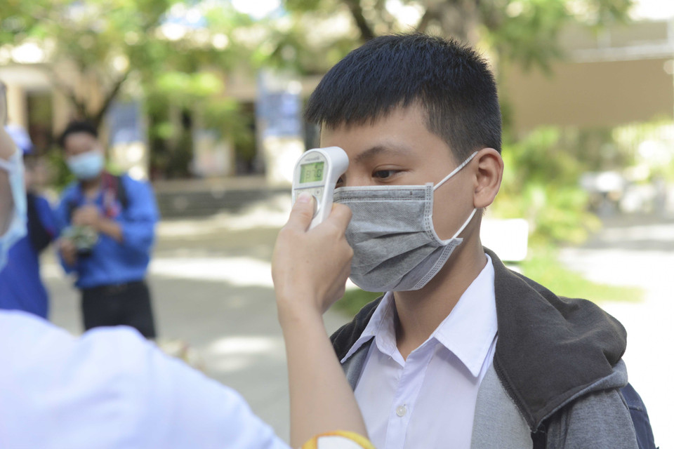 Học sinh được đo thân nhiệt, rửa tay bằng nước sát khuẩn trước khi vào phòng thi. (Ảnh: Văn Dũng/TTXVN)