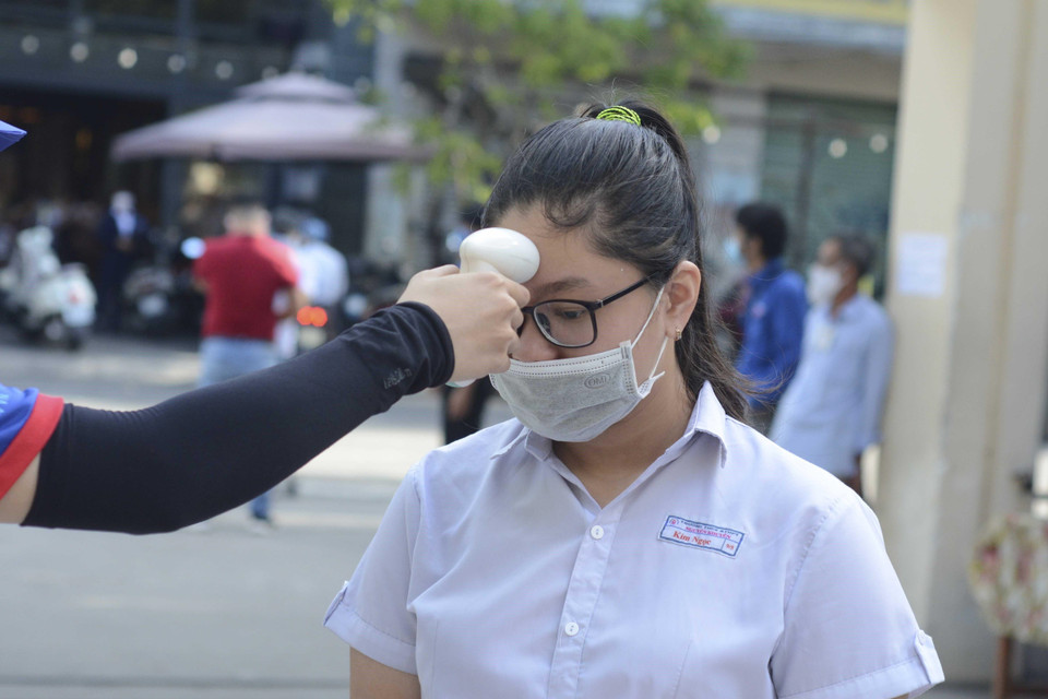 Học sinh được đo thân nhiệt, rửa tay bằng nước sát khuẩn trước khi vào phòng thi. (Ảnh: Văn Dũng/TTXVN)