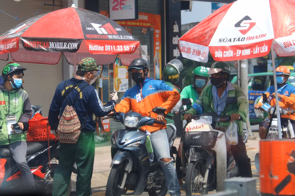 Rất đông những người giao hàng (shipper) tại giao lộ đường Phạm Văn Đồng-Phan Văn Trị (quận Gò Vấp). (Ảnh: Thanh Vũ/TTXVN)