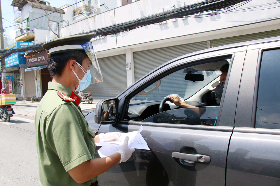 Lực lượng trực chốt kiểm tra giấy tờ ra đường của người dân tại chốt kiểm soát cầu Chợ Cầu (phía quận Gò Vấp). (Ảnh: Tiến Lực/TTXVN)