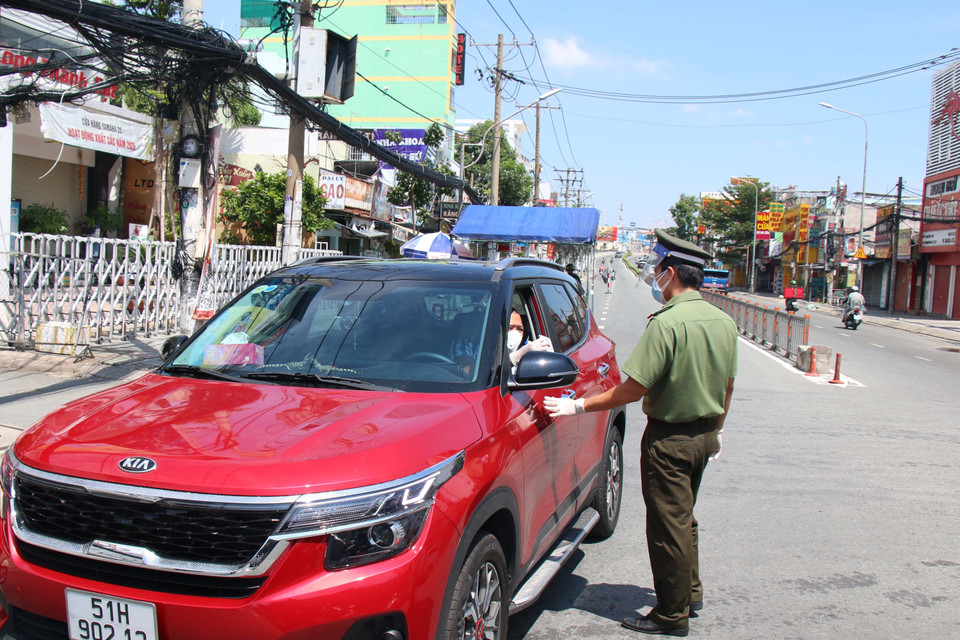 Lực lượng công an tại chốt kiểm soát cầu Chợ Cầu (Gò Vấp) kiểm tra giấy tờ người đi đường. (Ảnh: Tiến Lực/TTXVN)