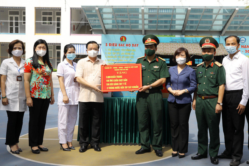 Bí thư Thành ủy Hà Nội Đinh Tiến Dũng trao quà hỗ trợ phòng, chống dịch bệnh COVID-19 tại Khu vực dự phòng cách ly y tế (Trường Tiểu học Phú Thượng, phường Phú Thượng, quận Tây Hồ, Hà Nội). (Ảnh: Nguyễn Điệp/TTXVN)