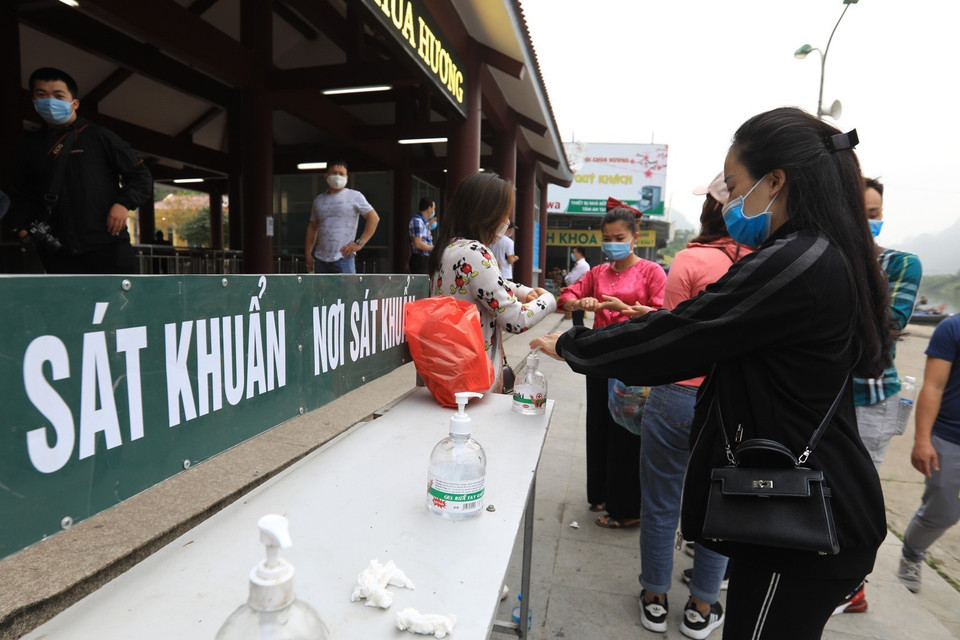 Trước cửa vào ga cáp treo chùa Hương được bố trí biển hướng dẫn quét mã QR-code để khai báo y tế và dung dịch rửa tay sát khuẩn cho du khách. (Ảnh: Thành Đạt/TTXVN) 