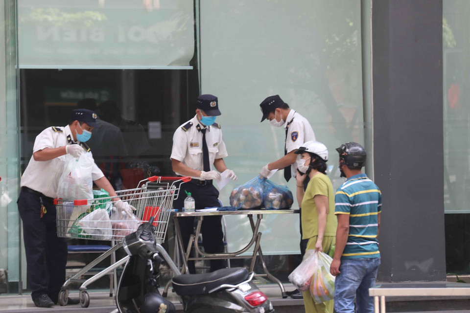 Lực lượng bảo vệ giúp người dân chuyển nhu yếu phẩm. (Ảnh: Thanh Tùng/TTXVN)