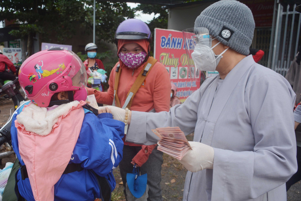 Đại diện chùa Thiên An (thành phố Buôn Ma Thuột) hỗ trợ tiền cho em nhỏ cùng cha mẹ về quê đi qua địa bàn tỉnh Đắk Lắk. (Ảnh: Hoài Thu/TTXVN)