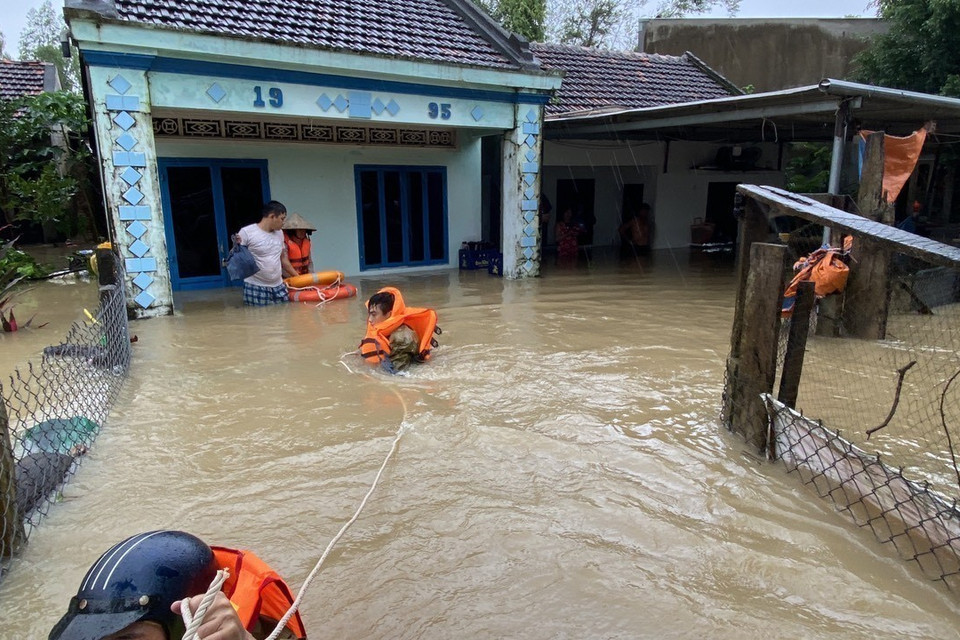 Công an huyện Tuy Phước (Bình Định) dầm mình trong nước lũ hỗ trợ di chuyển người dân. (Ảnh: Tường Quân/TTXVN)